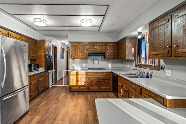 kitchen featuring light countertops, a sink, under cabinet range hood, and black appliances