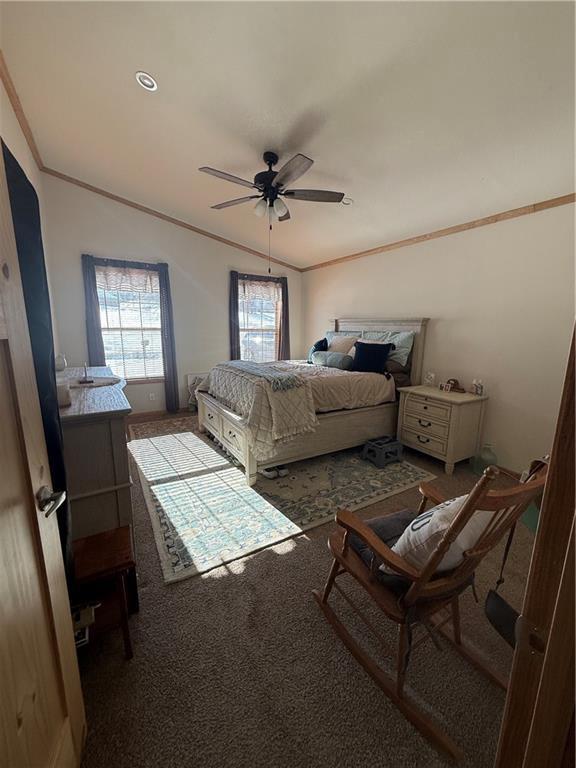 carpeted bedroom with lofted ceiling, ceiling fan, and ornamental molding