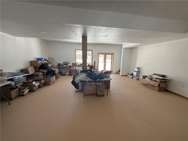 below grade area featuring french doors, carpet flooring, a textured ceiling, and baseboards