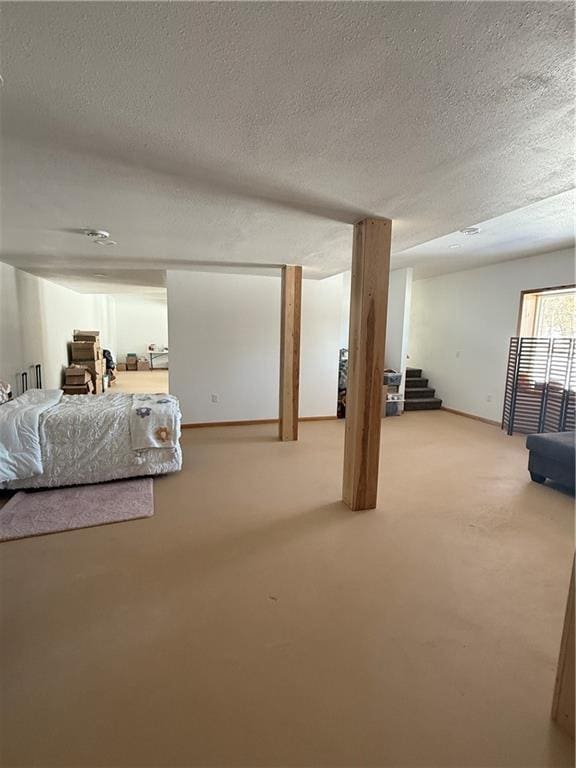 basement featuring a textured ceiling, carpet floors, and stairway