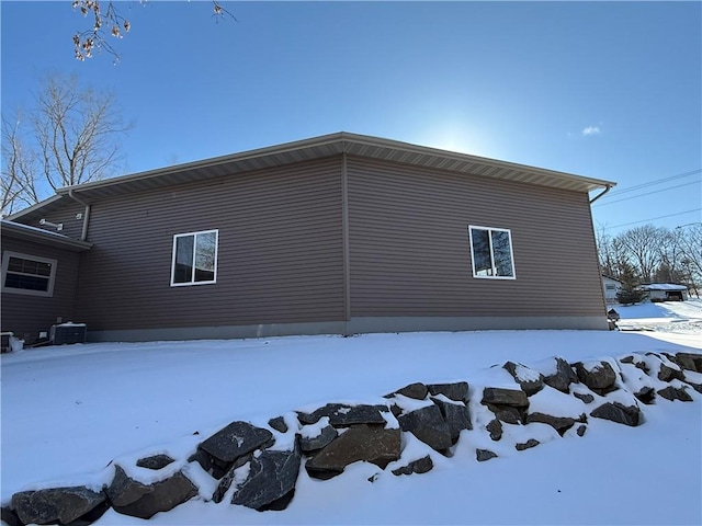 snow covered property with central AC