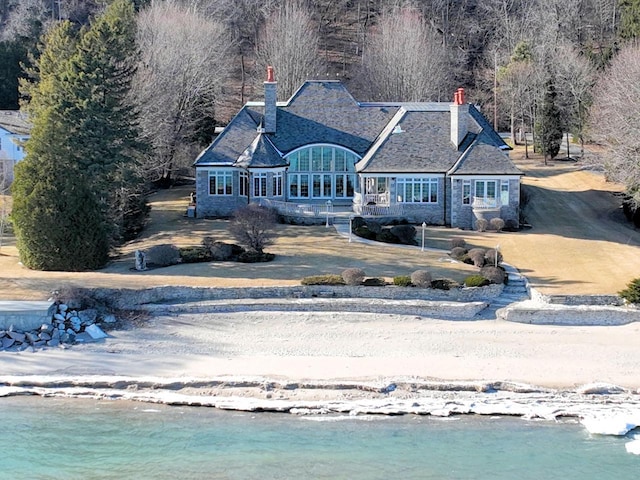 exterior space with stone siding, driveway, and a chimney