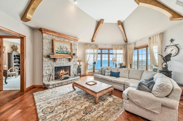 living room with a stone fireplace, lofted ceiling with beams, baseboards, and wood finished floors