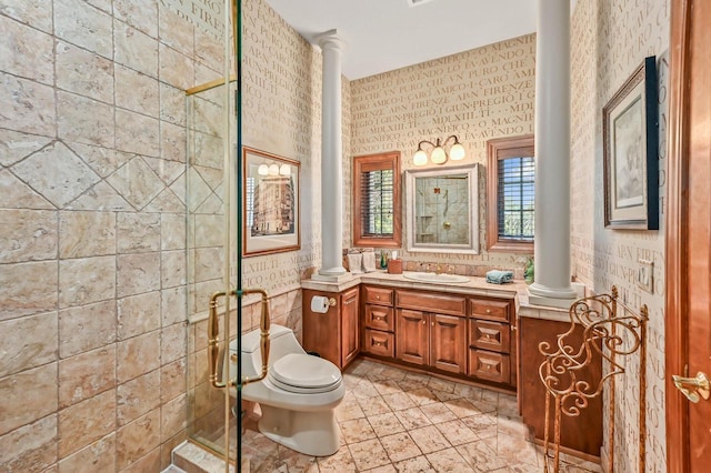 bathroom featuring toilet, decorative columns, vanity, and a stall shower