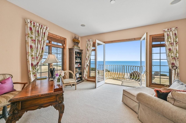 carpeted living area with a water view