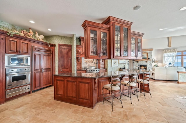 kitchen featuring glass insert cabinets, built in appliances, dark stone counters, a peninsula, and a warming drawer