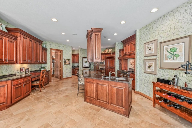 kitchen with a sink, premium appliances, a breakfast bar, and wallpapered walls