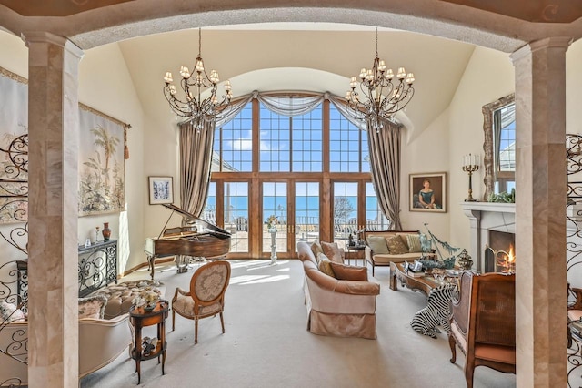 carpeted living room featuring decorative columns, plenty of natural light, and an inviting chandelier