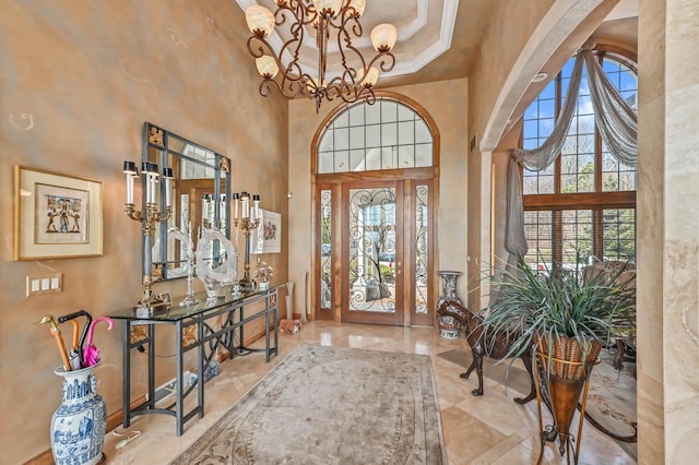 foyer entrance with a towering ceiling, a wealth of natural light, and a chandelier