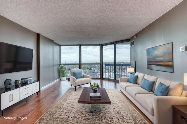 living room featuring a textured ceiling, wood finished floors, visible vents, baseboards, and expansive windows