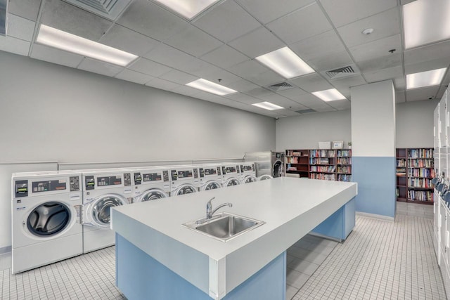 common laundry area with independent washer and dryer, light tile patterned flooring, a sink, and visible vents