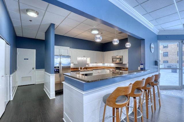 kitchen with stainless steel appliances, dark wood finished floors, white cabinetry, and a sink