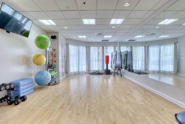 workout area with light wood finished floors, plenty of natural light, visible vents, and baseboards