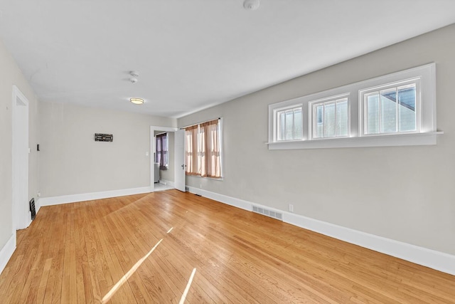 empty room with light wood-type flooring, baseboards, and visible vents