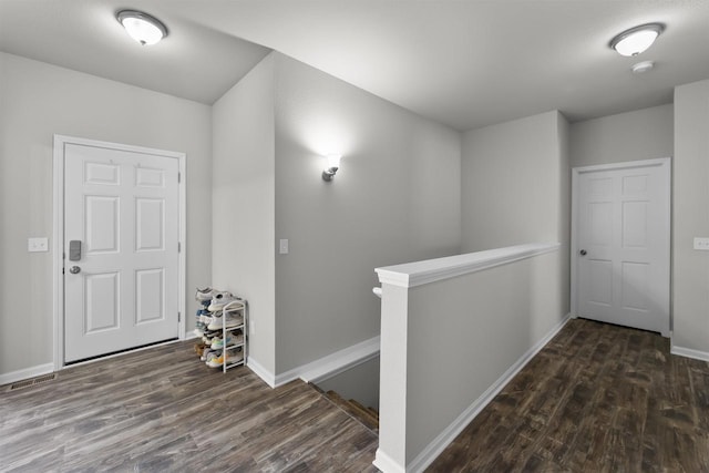 corridor featuring dark wood-style flooring, baseboards, and an upstairs landing