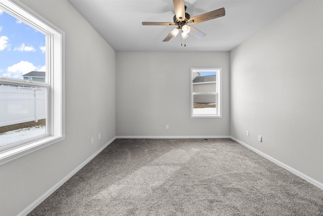 carpeted empty room with ceiling fan and baseboards