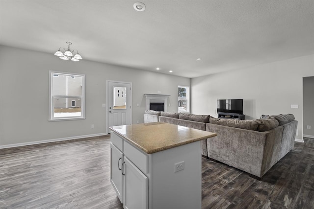 kitchen featuring dark wood-type flooring, white cabinetry, open floor plan, light countertops, and a center island