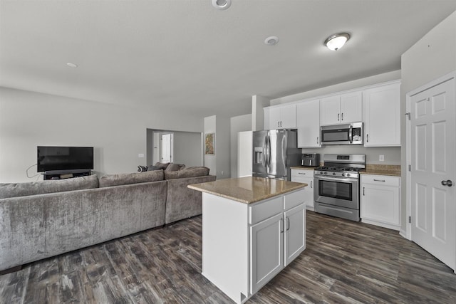 kitchen featuring open floor plan, appliances with stainless steel finishes, a kitchen island, and white cabinetry