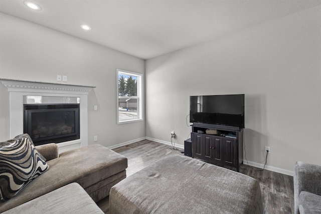 living area featuring dark wood-type flooring, recessed lighting, a glass covered fireplace, and baseboards