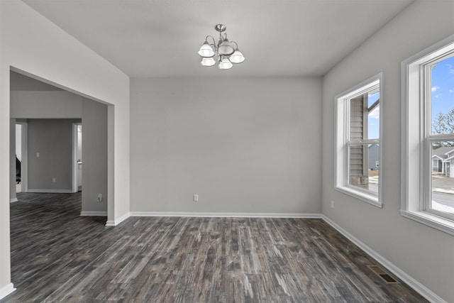 unfurnished room featuring visible vents, baseboards, dark wood finished floors, and a chandelier