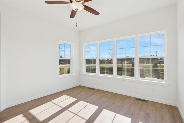 empty room with light wood-type flooring, visible vents, and baseboards