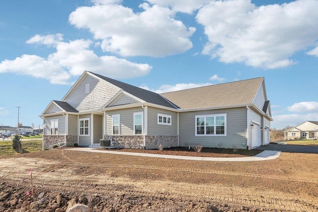 exterior space featuring a garage, cooling unit, and stone siding