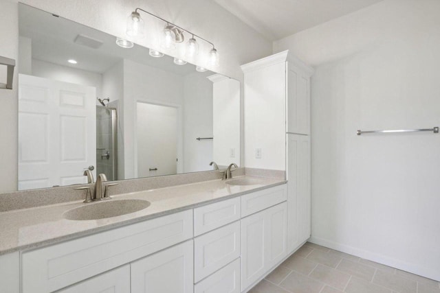 bathroom with baseboards, double vanity, a sink, and a shower stall