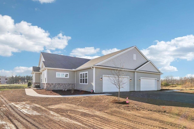 ranch-style house with aphalt driveway, stone siding, a garage, and central air condition unit