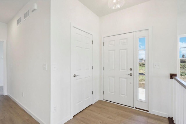 foyer entrance featuring visible vents, light wood-style flooring, and baseboards