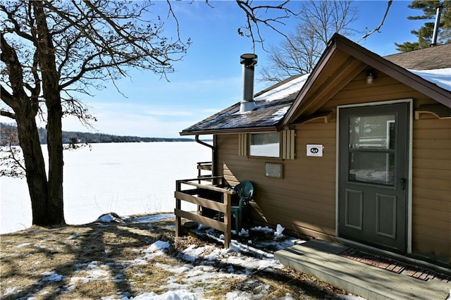 snow covered property with a shingled roof