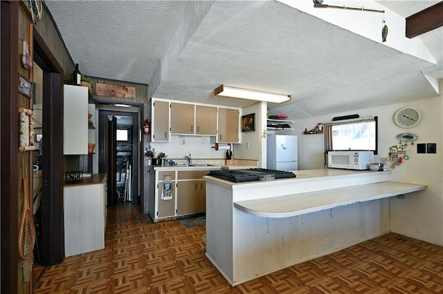 kitchen featuring white appliances, a peninsula, light countertops, a textured ceiling, and a sink