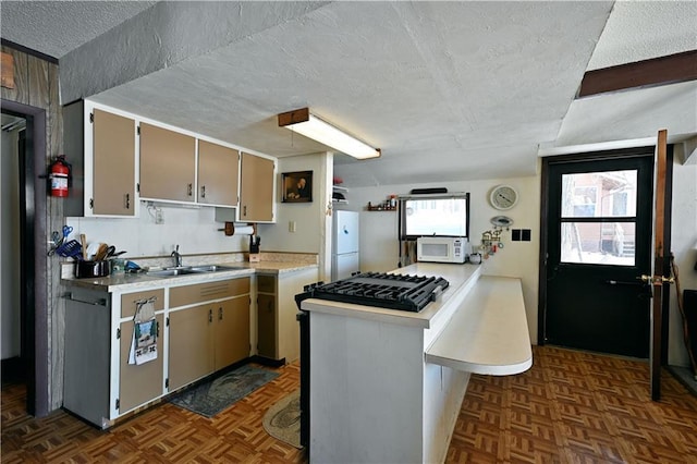 kitchen with white appliances, light countertops, a sink, and a textured ceiling