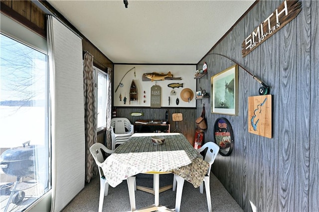 carpeted dining area with wood walls