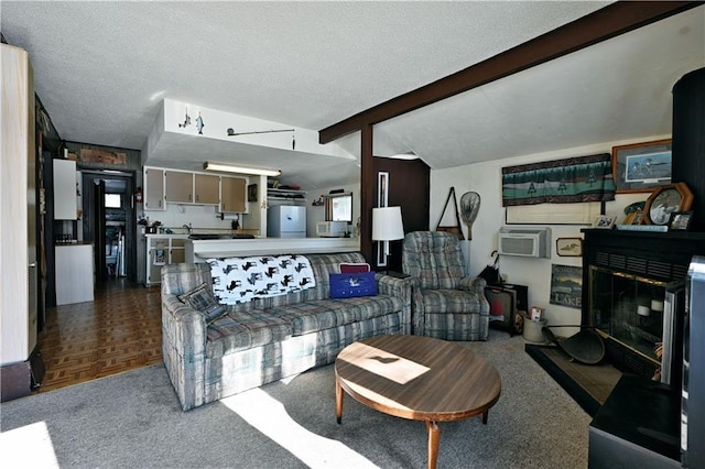 living area featuring lofted ceiling with beams, a wall mounted AC, a textured ceiling, and a glass covered fireplace