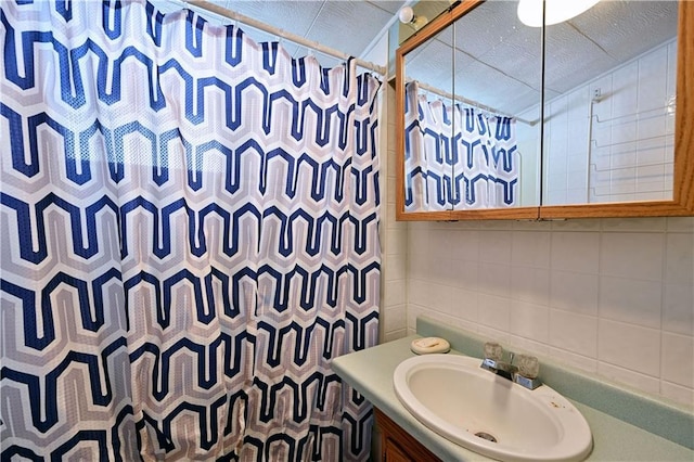 bathroom with a shower with curtain, backsplash, tile walls, and vanity