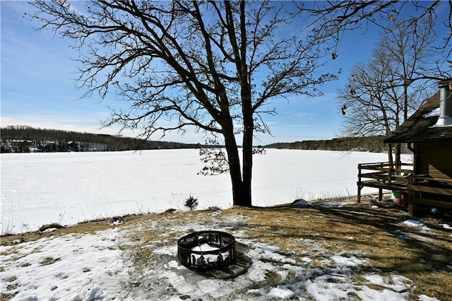 yard layered in snow with a water view and an outdoor fire pit