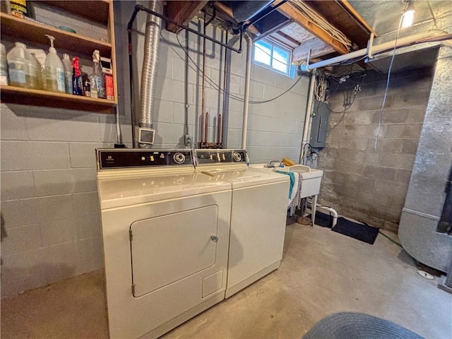 washroom with laundry area, washing machine and dryer, electric panel, and a sink