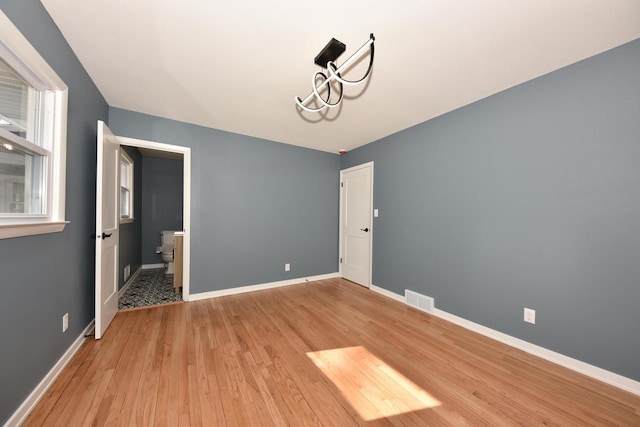 unfurnished room with light wood-type flooring, visible vents, and baseboards