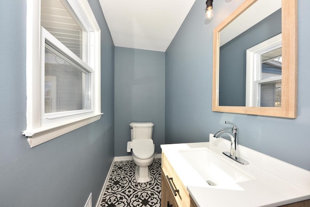 half bathroom with baseboards, visible vents, vanity, and toilet