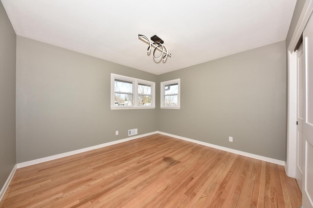 spare room featuring light wood-style floors, visible vents, and baseboards