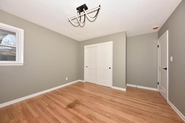 unfurnished bedroom with light wood finished floors, baseboards, and a closet