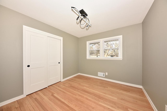 interior space with light wood-style floors, visible vents, and baseboards