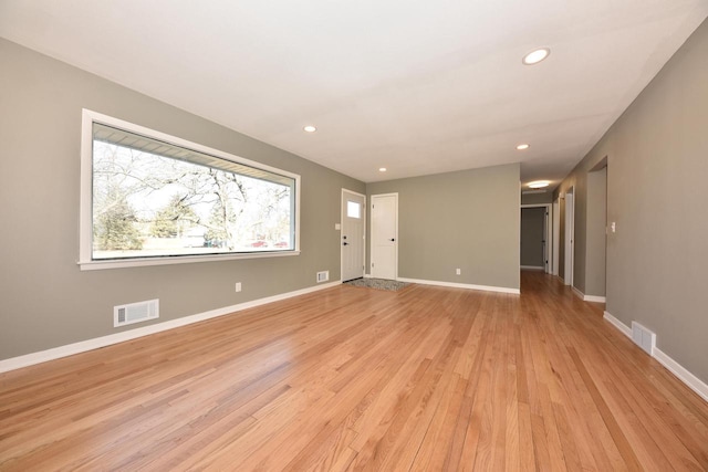 empty room with light wood-style floors, baseboards, and visible vents