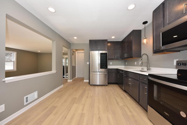 kitchen featuring visible vents, appliances with stainless steel finishes, hanging light fixtures, light countertops, and a sink