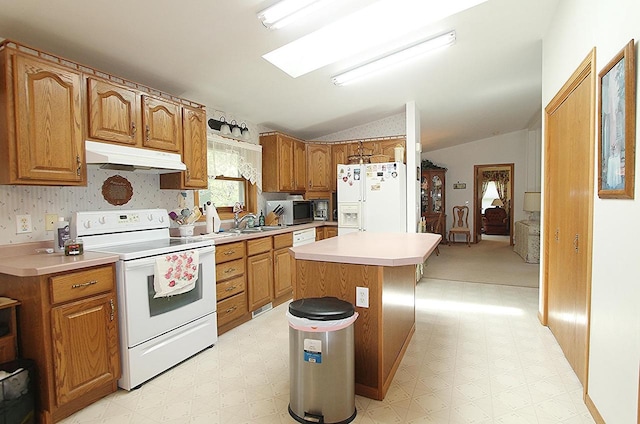 kitchen with white appliances, vaulted ceiling with skylight, under cabinet range hood, and light floors