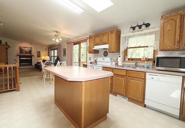 kitchen with white appliances, a sink, under cabinet range hood, and light floors