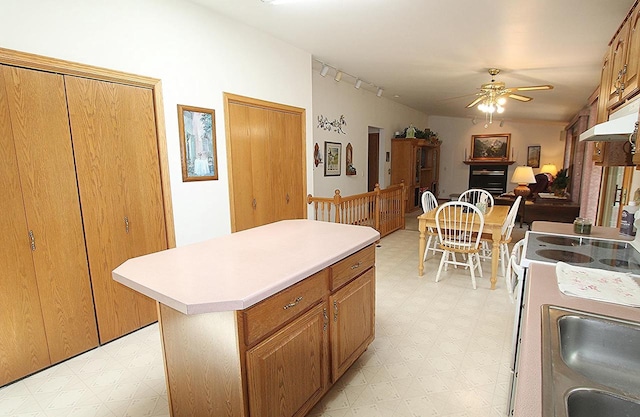 kitchen featuring a ceiling fan, a center island, light countertops, and light floors