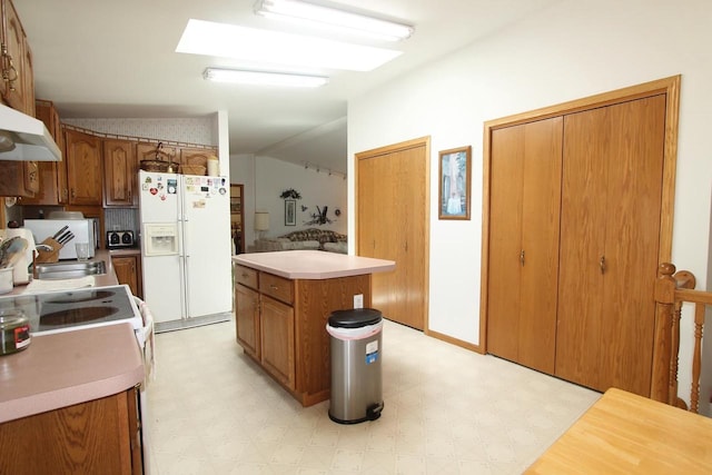 kitchen featuring a center island, brown cabinets, light floors, light countertops, and white appliances