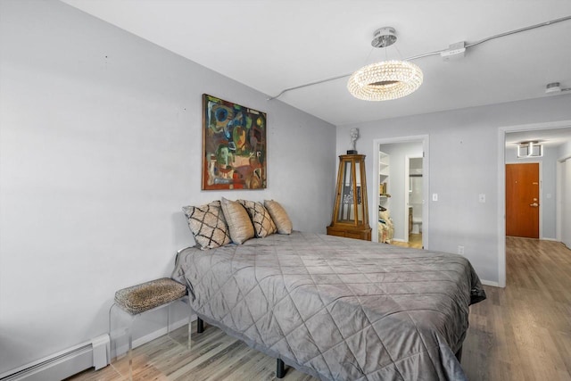 bedroom with a chandelier, baseboards, baseboard heating, and wood finished floors