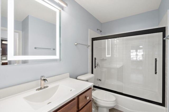 bathroom featuring combined bath / shower with glass door, vanity, and toilet